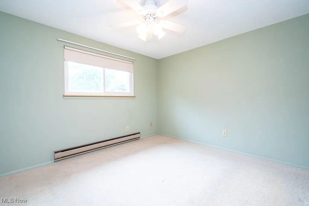 Unfurnished room with a baseboard heating unit, carpet, and a ceiling fan