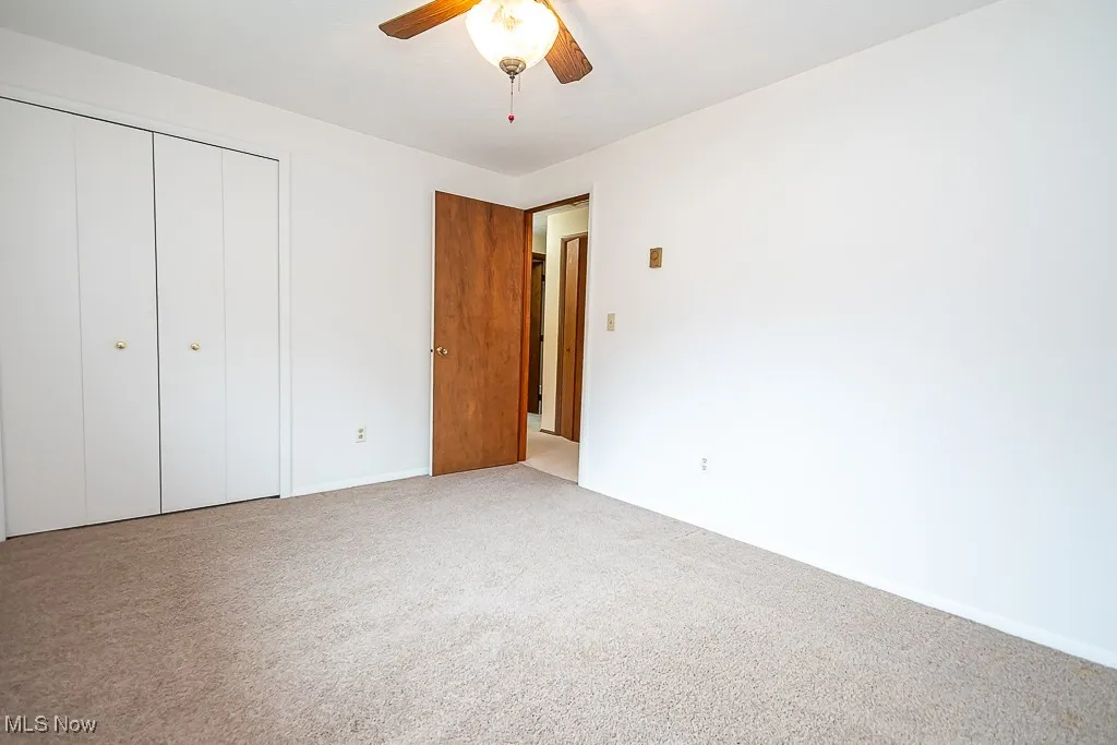 Unfurnished bedroom featuring carpet floors, a closet, and a ceiling fan