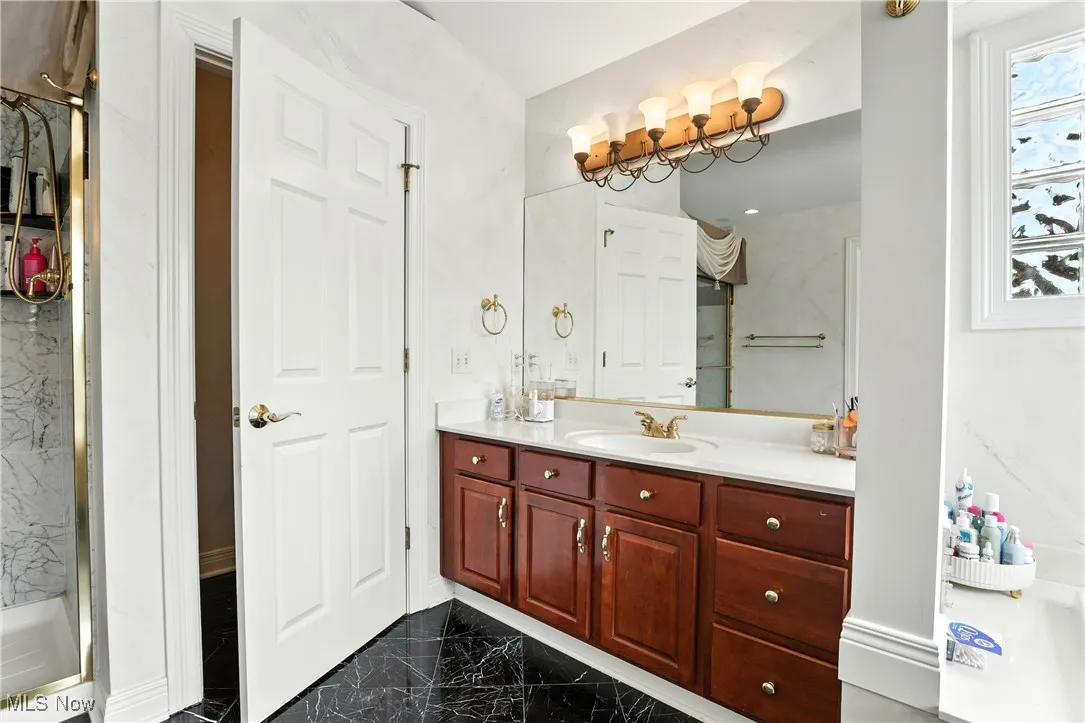 Bathroom featuring marble tiled floors, vanity, and a walk in shower