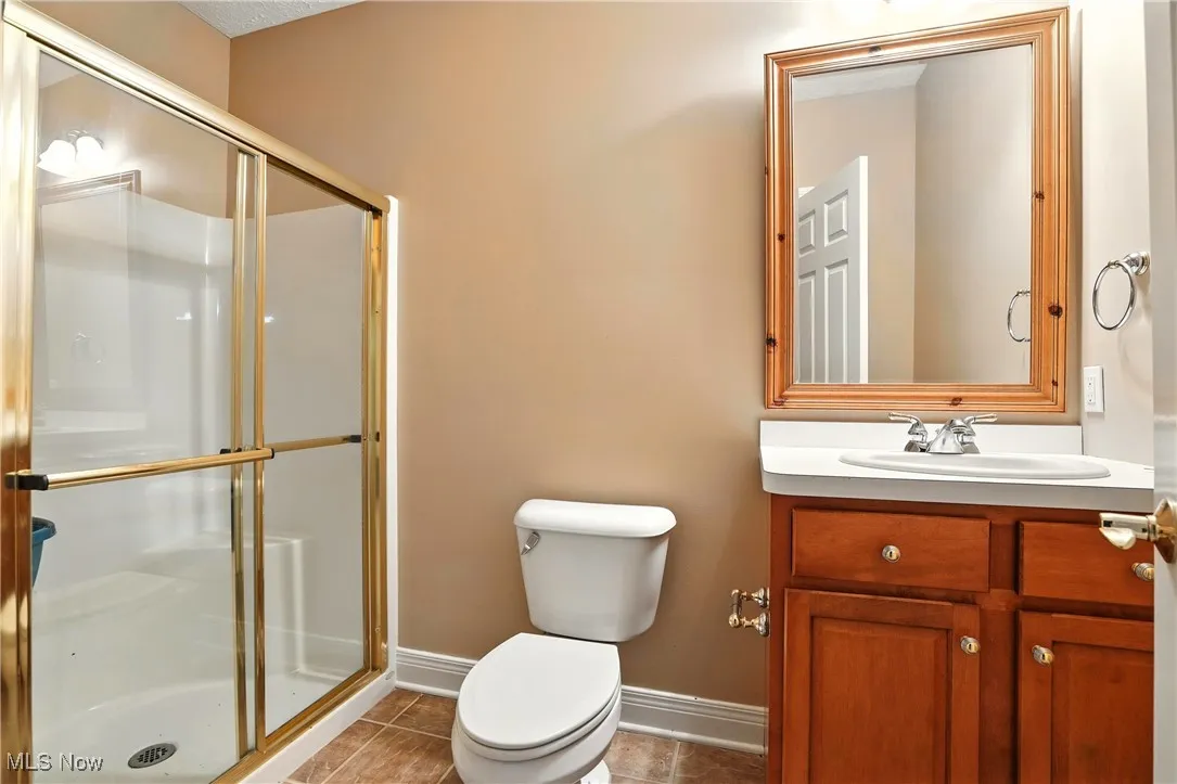 Full bathroom featuring a stall shower, vanity, and tile patterned flooring