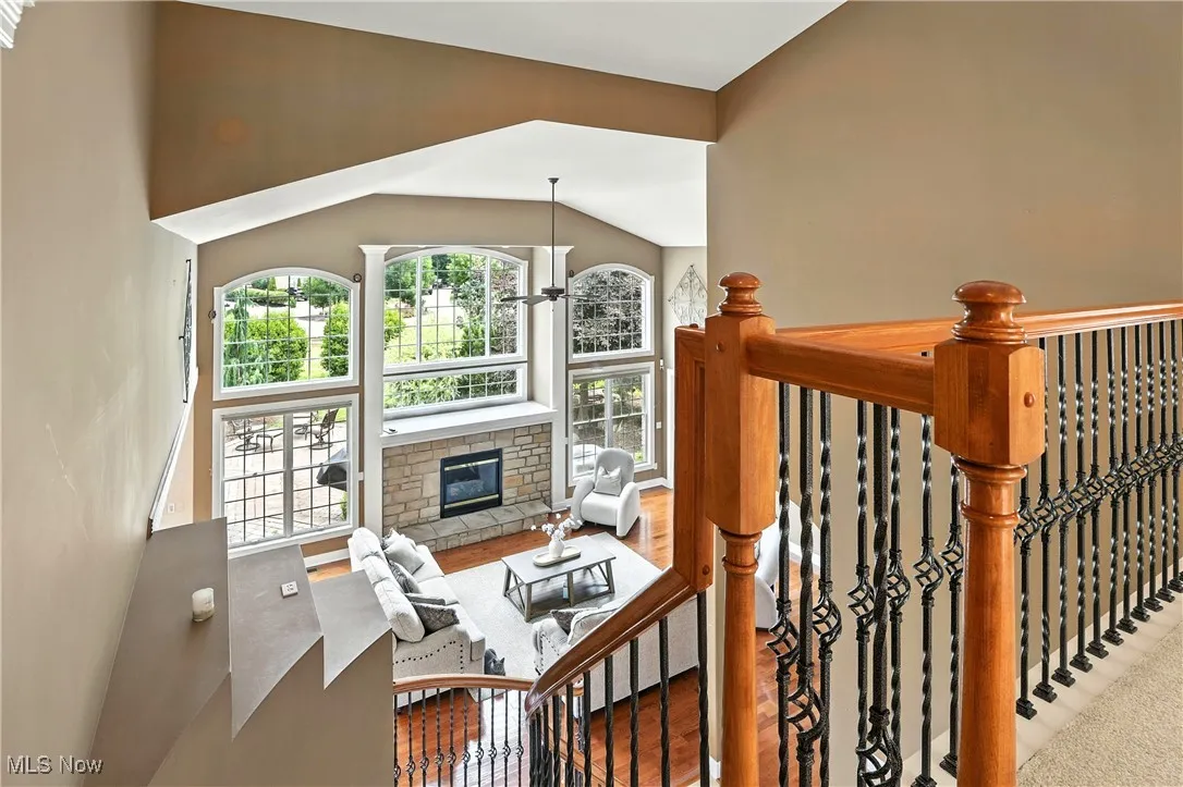 Stairway featuring a stone fireplace, high vaulted ceiling, and wood finished floors