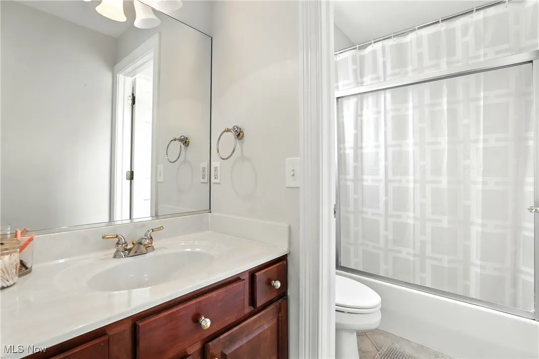 Bathroom featuring vanity, shower / bath combo, and tile patterned flooring