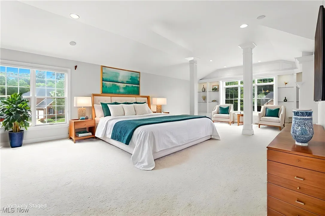 Carpeted bedroom with ornate columns, lofted ceiling, multiple windows, and recessed lighting