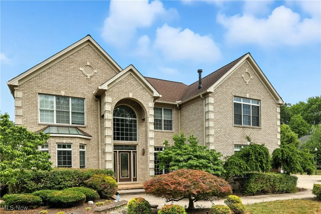 Traditional home featuring brick siding and a shingled roof