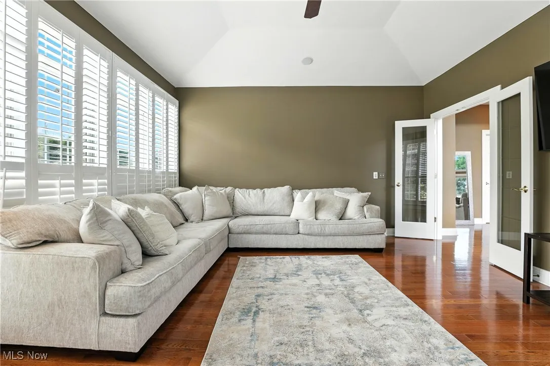 Living area with dark wood-style flooring, lofted ceiling, and ceiling fan