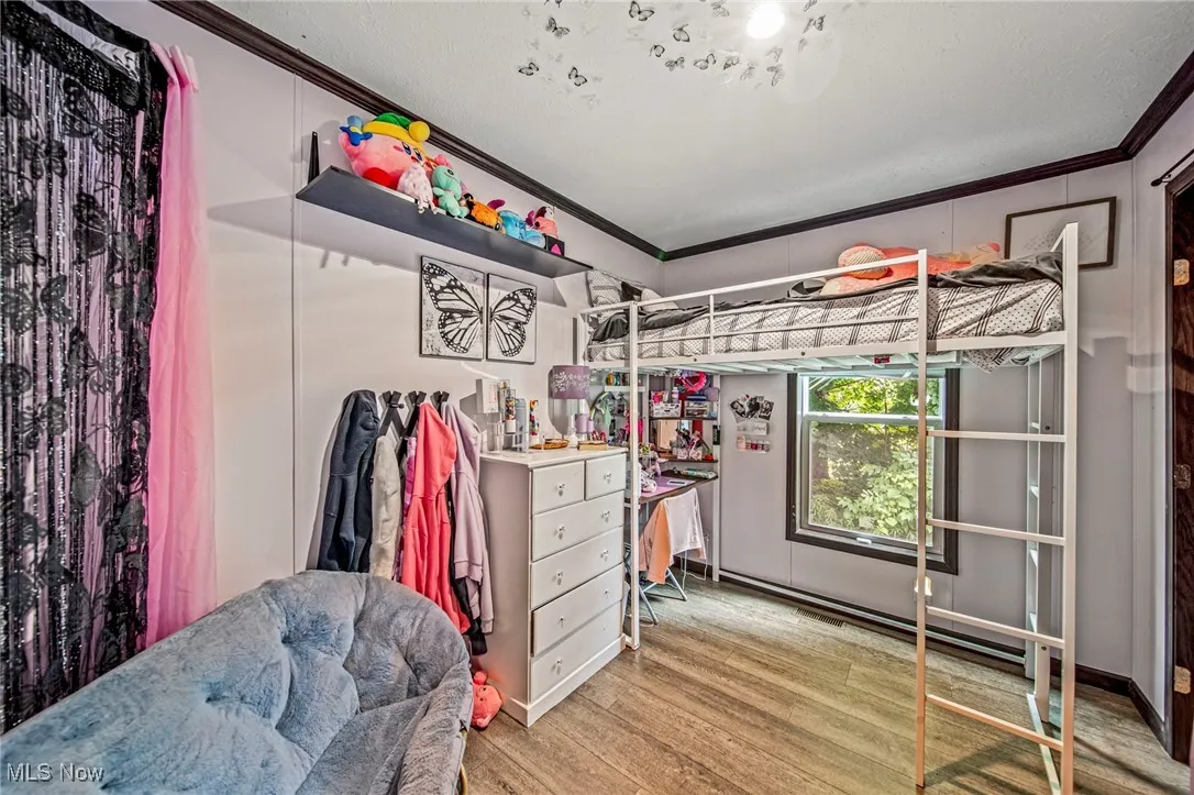 Bedroom featuring crown molding and wood finished floors