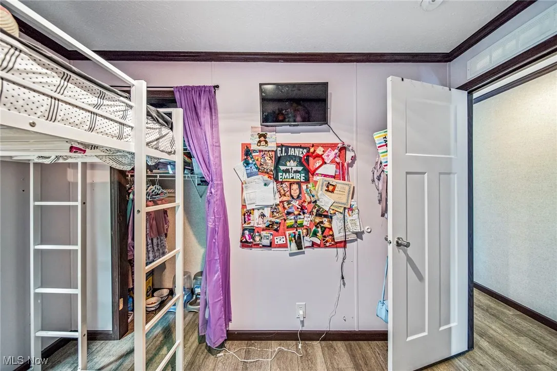 Bedroom with ornamental molding and wood finished floors