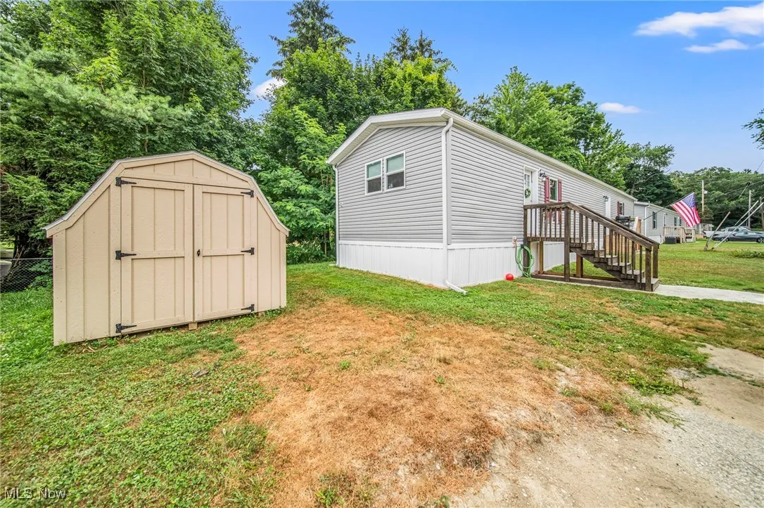 View of side of home with a shed and view of wooded area