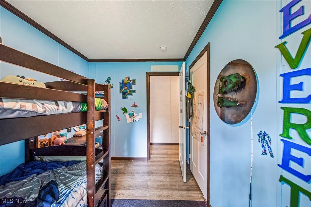 Bedroom with crown molding, wood finished floors, and a textured ceiling