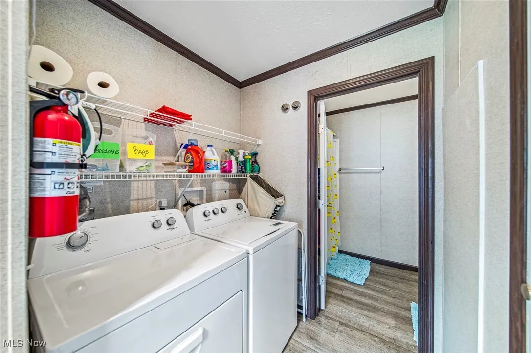 Laundry area with ornamental molding, light wood-type flooring, separate washer and dryer, and water heater