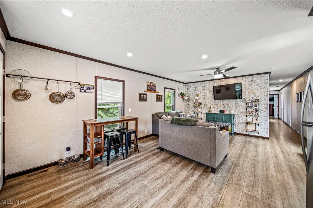 Living area with wood finished floors, crown molding, a textured ceiling, a ceiling fan, and recessed lighting