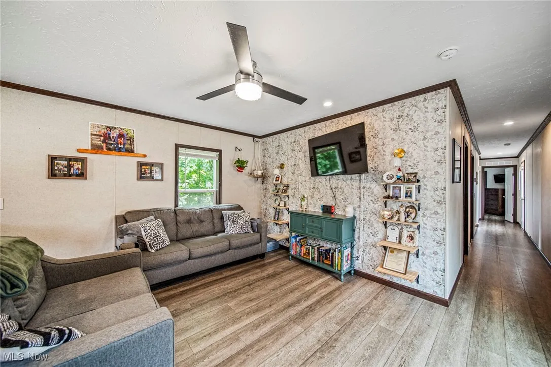 Living room with crown molding, wood finished floors, and a ceiling fan