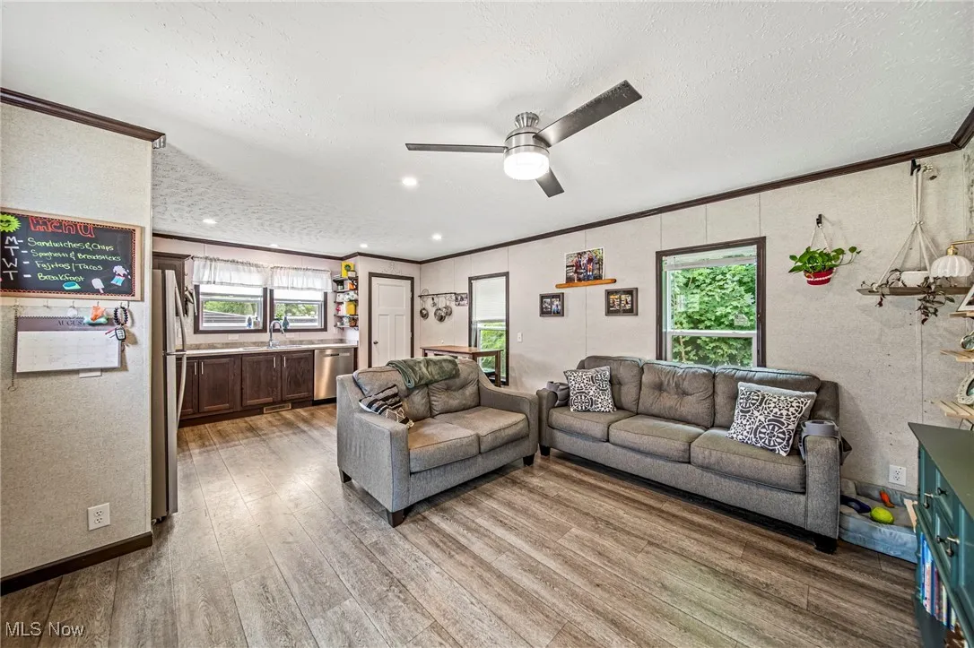 Living area with crown molding, light wood-style flooring, a ceiling fan, a textured ceiling, and recessed lighting