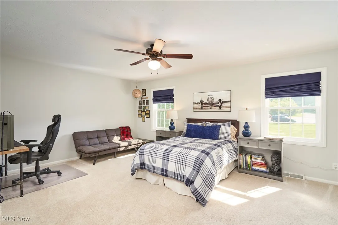 Bedroom featuring carpet flooring, multiple windows, and ceiling fan
