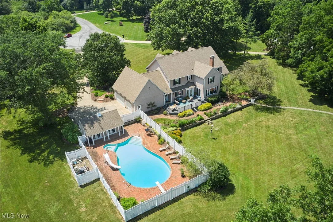 View of pool with a patio area, a fenced backyard, a water slide, and view of scattered trees