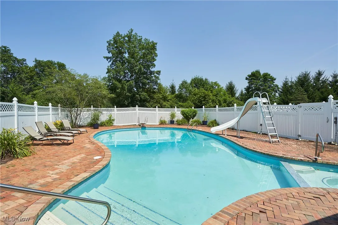 View of pool with diving board and slide.
