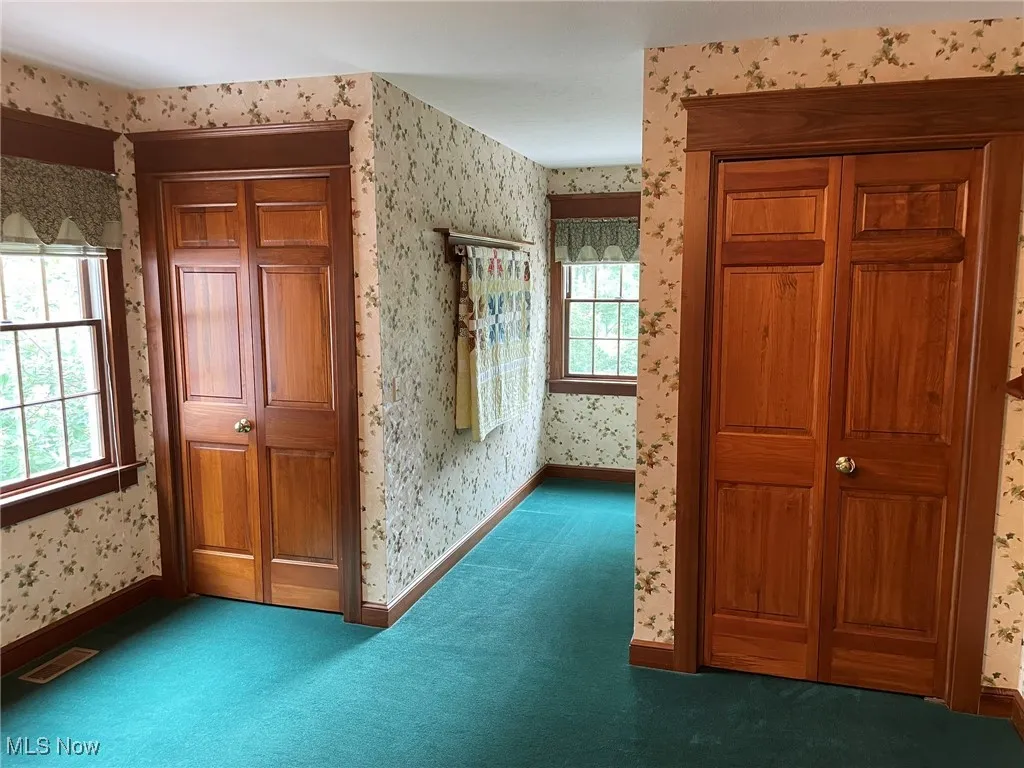 Hallway featuring wallpapered walls and carpet flooring