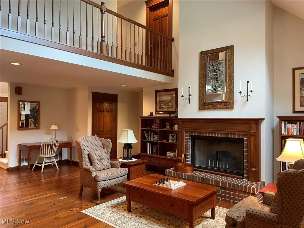 Living area with a towering ceiling, hardwood / wood-style flooring, a fireplace, and recessed lighting