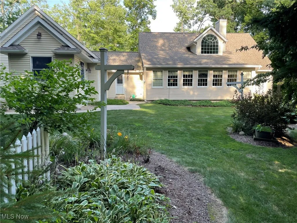 View of front facade featuring a front lawn, a chimney, and roof with shingles