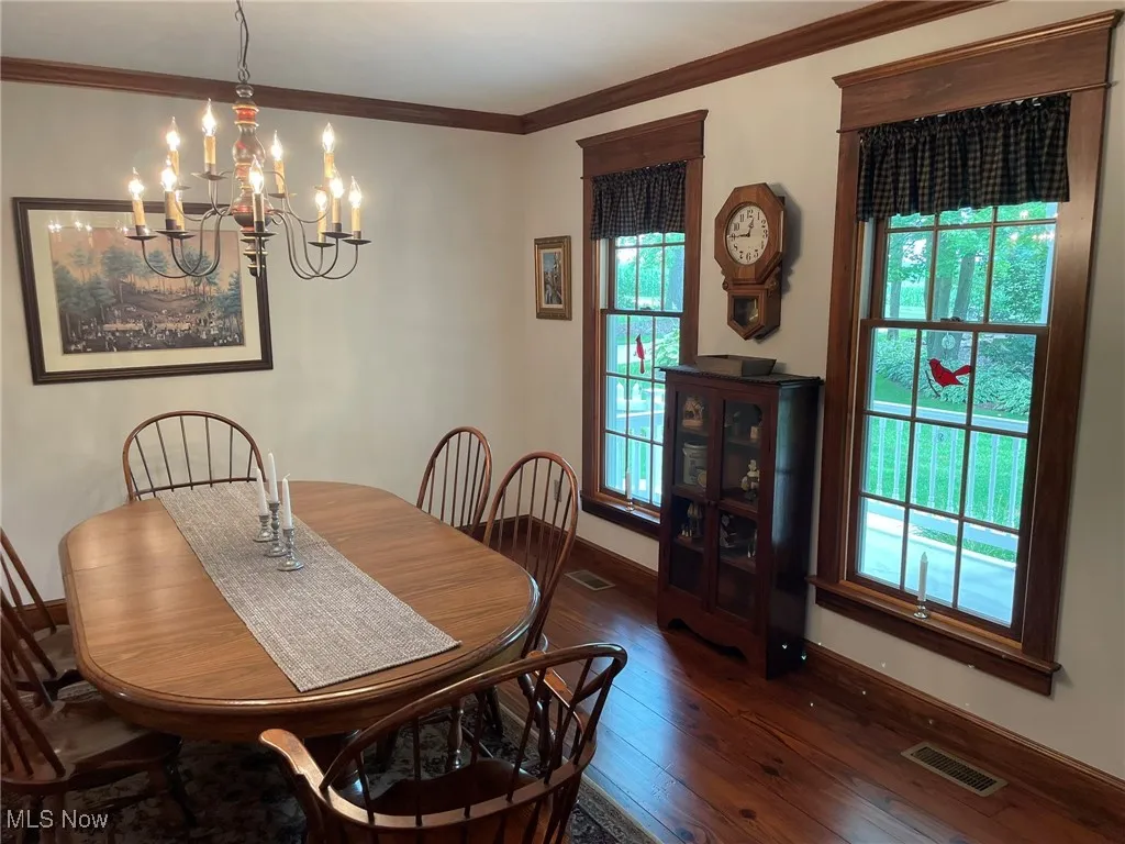 Dining room with hardwood / wood-style flooring, a chandelier, and ornamental molding