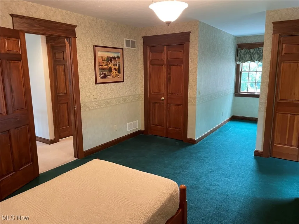 Unfurnished bedroom featuring carpet and wallpapered walls