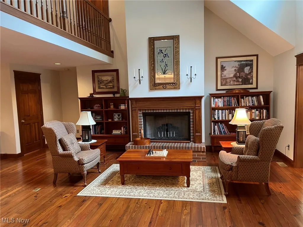 Living area featuring a high ceiling, wood-type flooring, and a brick fireplace