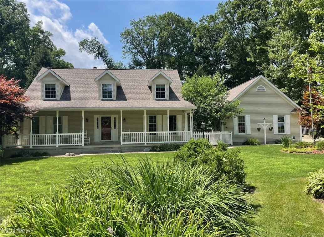 Cape cod-style house featuring a front yard, a porch, and a shingled roof