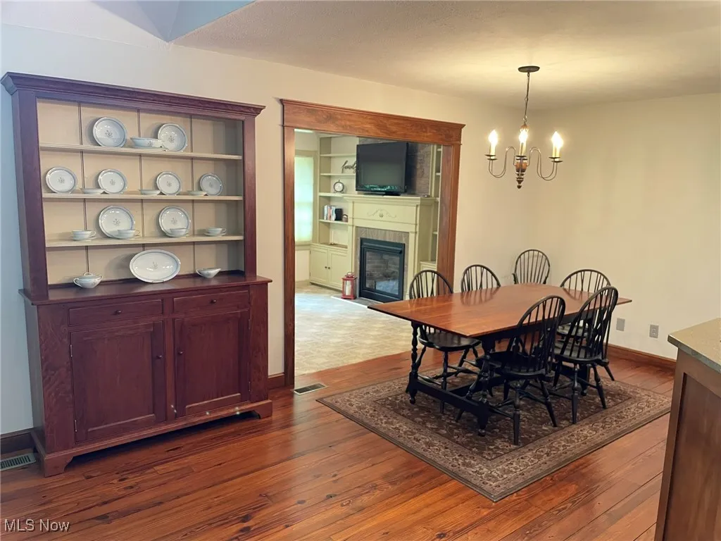 Dining room featuring a chandelier, a glass covered fireplace, and dark wood-type flooring