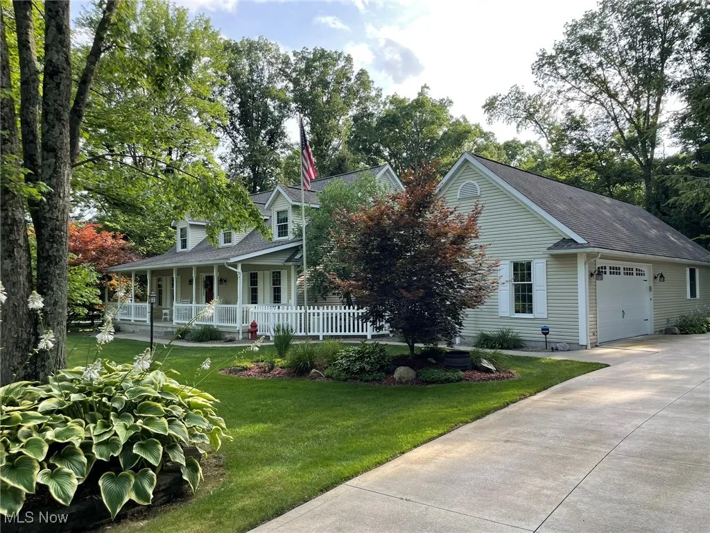 View of front of property with covered porch, a garage, concrete driveway, a front yard, and a shingled roof