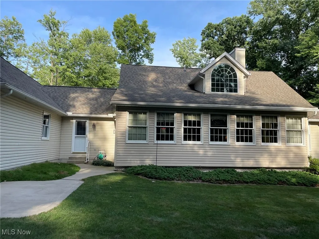 View of front of home featuring a front yard, a chimney, roof with shingles, and entry steps