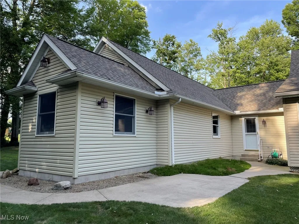 View of side of home featuring entry steps, a shingled roof, a patio area, and a yard