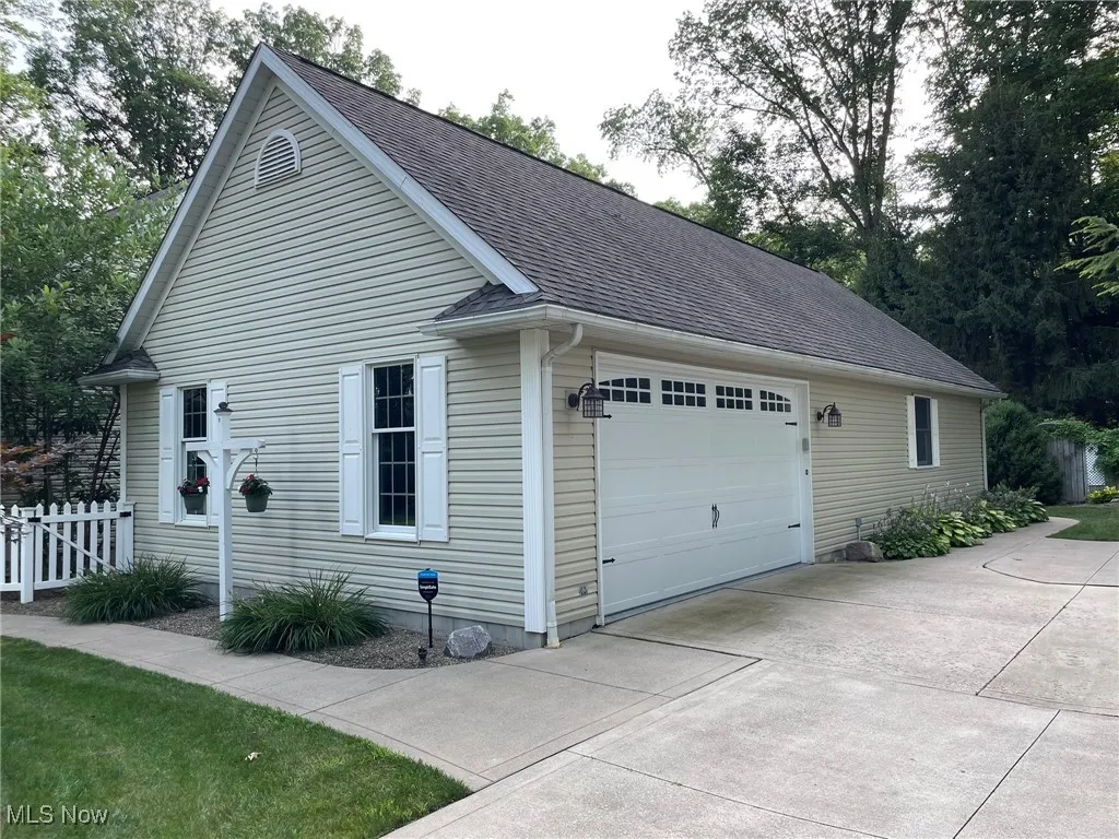 View of home's exterior featuring a garage, roof with shingles, and concrete driveway