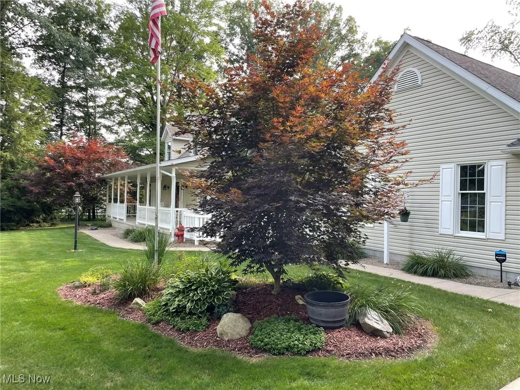 View of side of home featuring a lawn and a porch