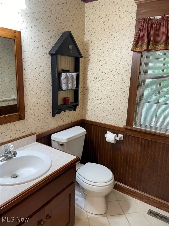 Bathroom featuring a wainscoted wall, wallpapered walls, vanity, and tile patterned flooring
