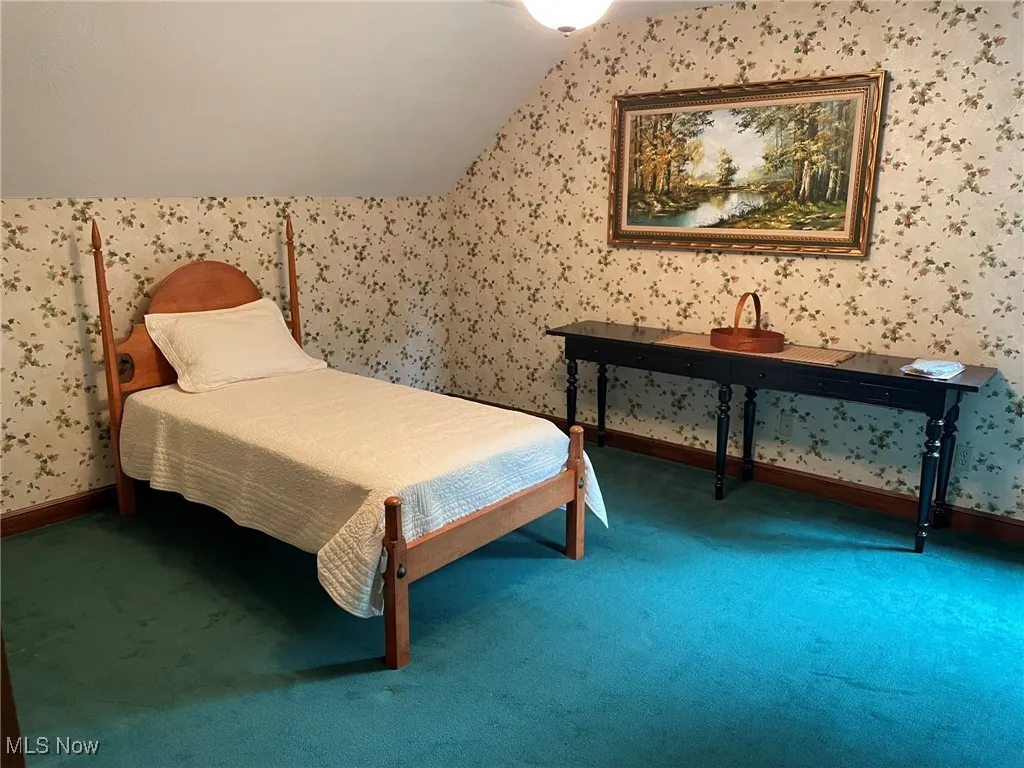 Carpeted bedroom featuring lofted ceiling and wallpapered walls