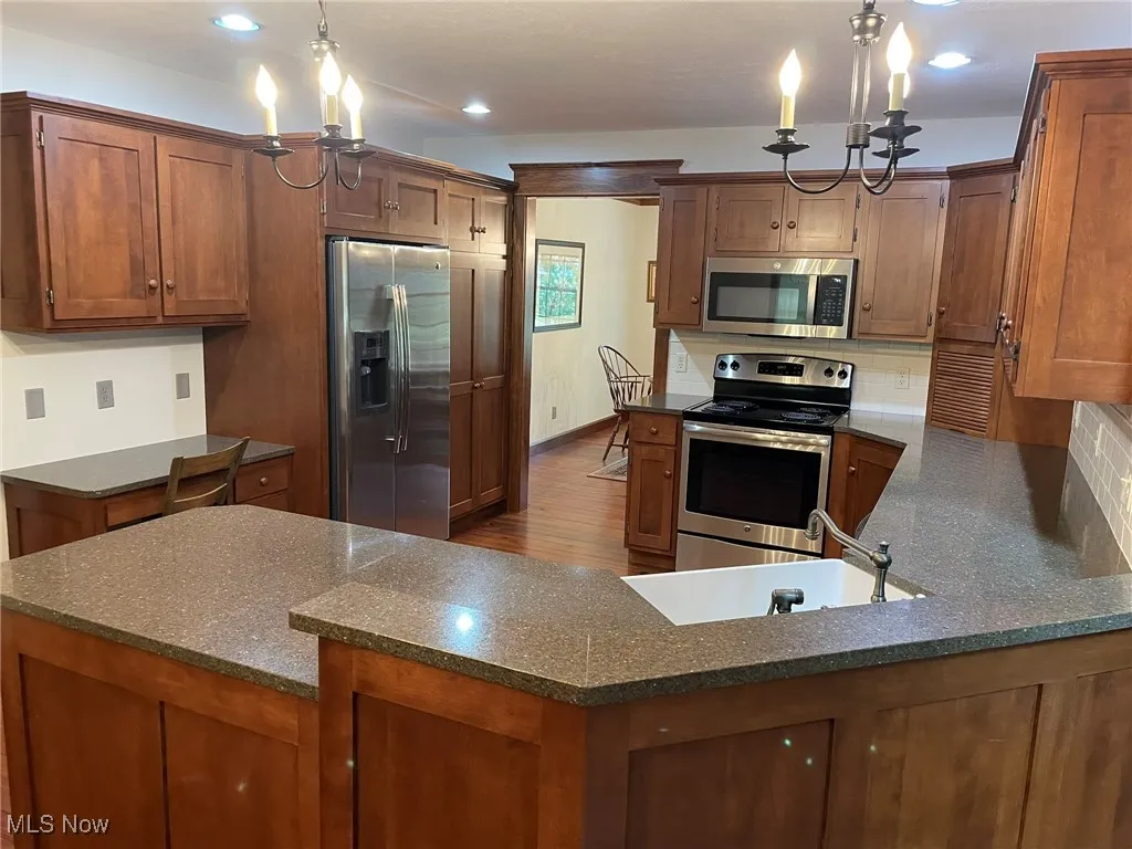 Kitchen with appliances with stainless steel finishes, brown cabinetry, decorative backsplash, recessed lighting, and dark wood-style floors
