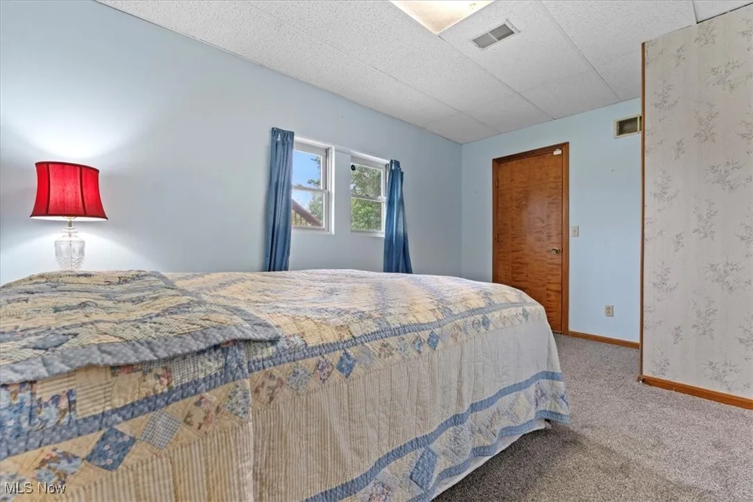 Carpeted bedroom with baseboards and a paneled ceiling located on the lower walk out level.  This room has a full bathroom.