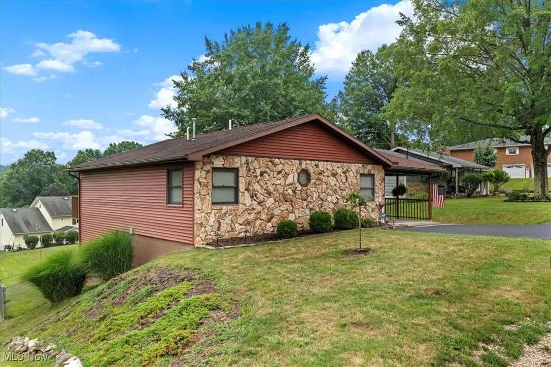 View of property exterior featuring a yard, driveway, and stone siding. Built in 1989.