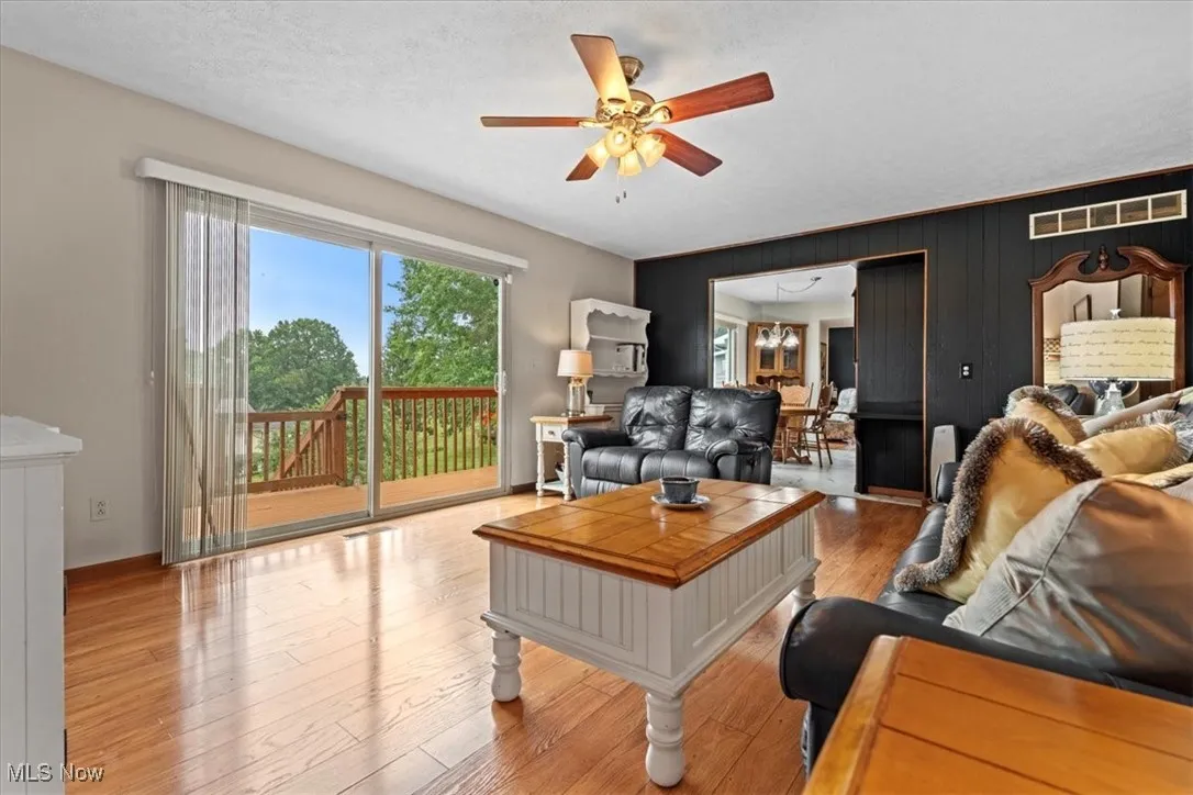 Living area with a ceiling fan and light wood-style flooring.  An 8 foot slider leads to the deck and stairs.