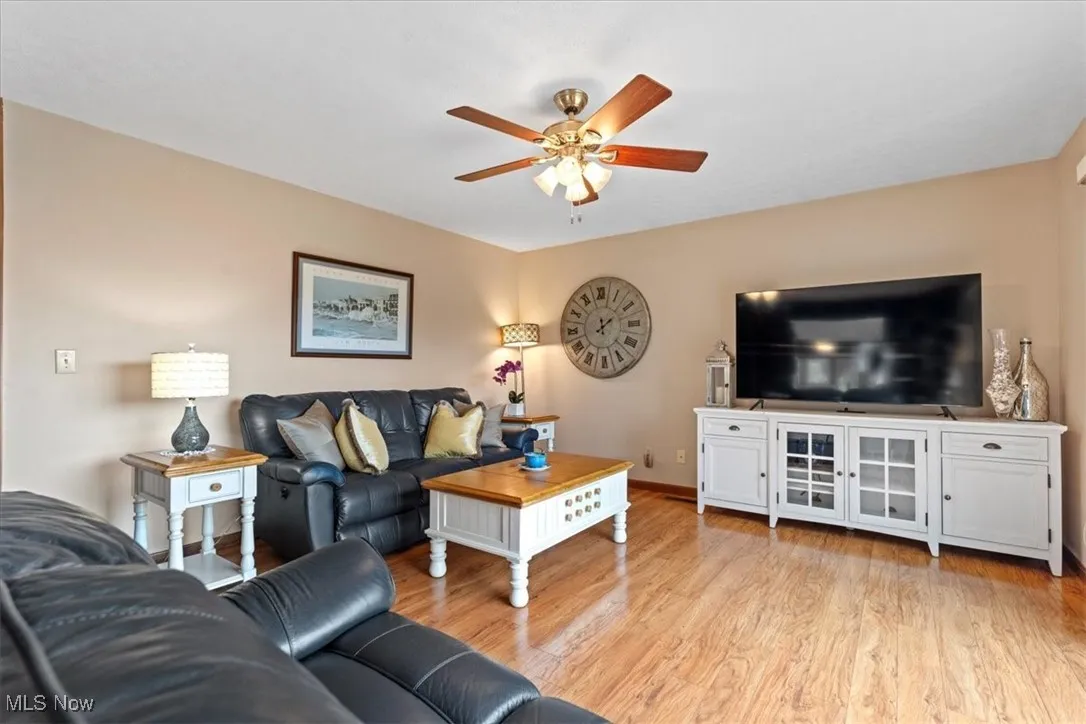 Living room with a ceiling fan and light wood-type flooring.