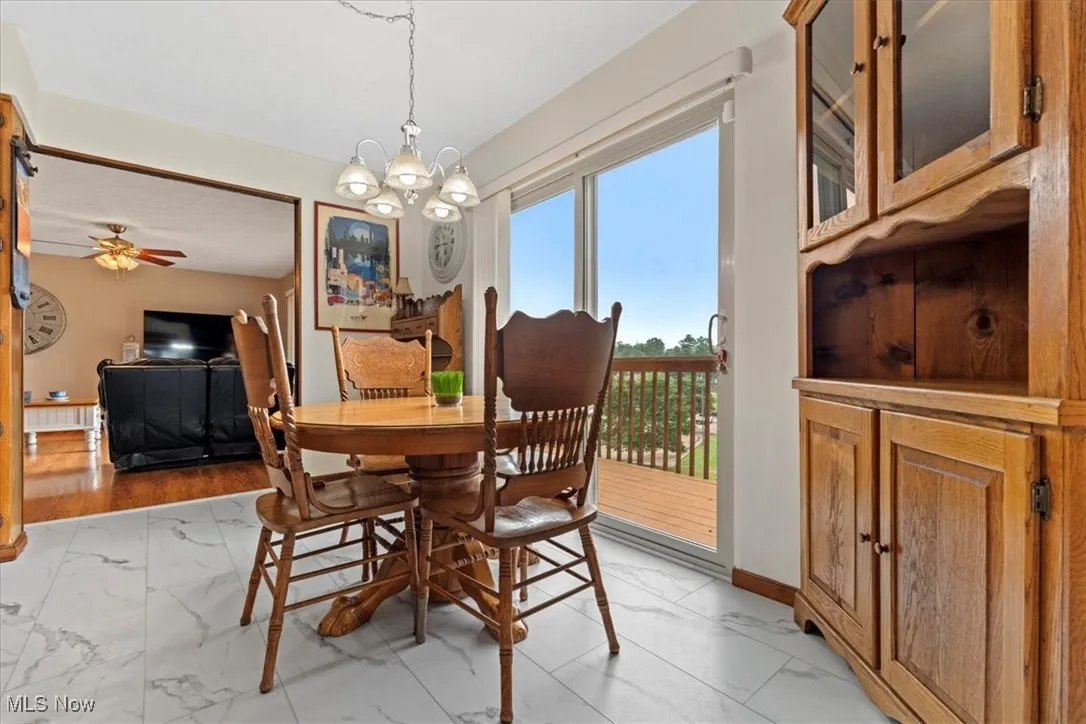 Eat in Kitchen with light marble finish floors, a chandelier, and a ceiling fan.
