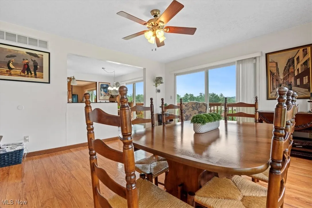 Dining area featuring light laminated finished floors, ceiling fan, and a 8 ft. glass sliding door. onto the deck.