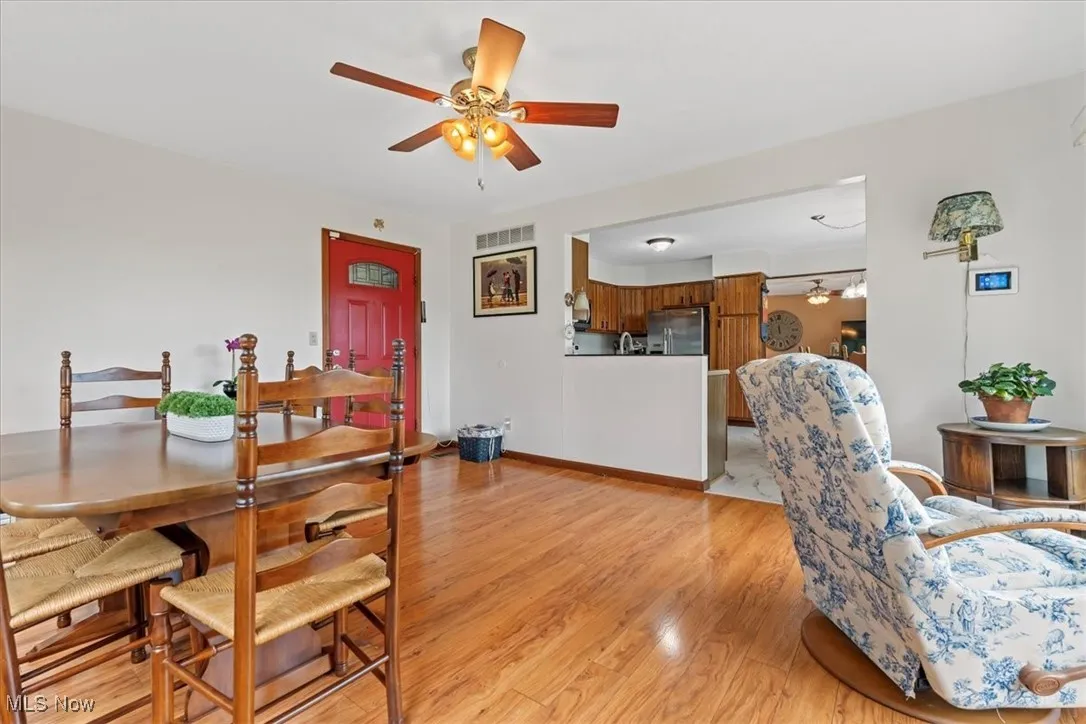 Dining space featuring light wood-style flooring and ceiling fan and an open concept to the kitchen and livingroom.  This is the entry door from the covered carport.