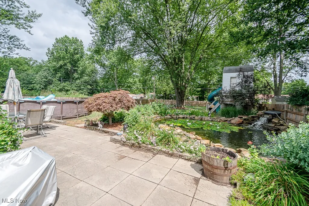 Fenced backyard featuring a patio area, a garden pond, and a storage unit