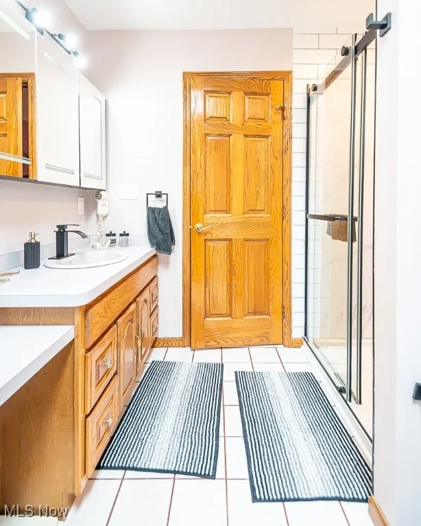 Full bathroom with vanity, a stall shower, and tile patterned floors