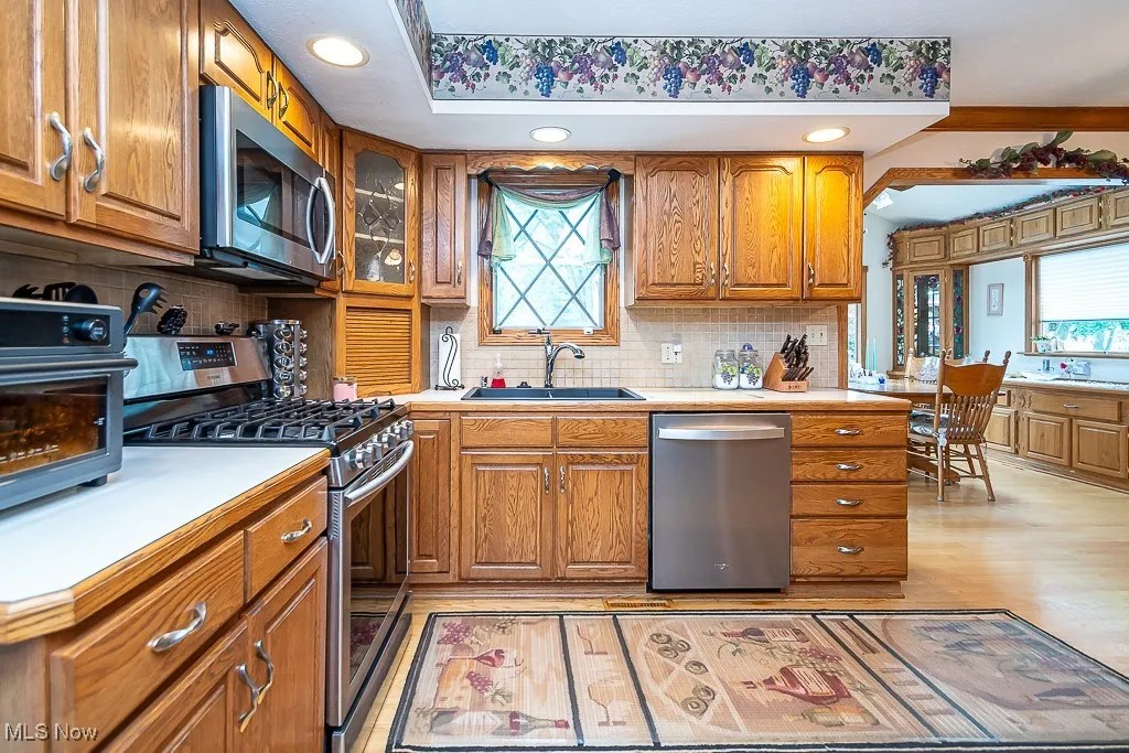 Kitchen with stainless steel appliances, light countertops, tasteful backsplash, and recessed lighting