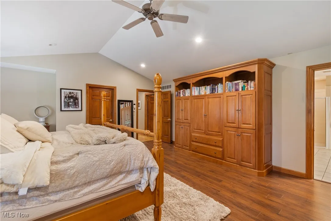 Bedroom with dark wood-style floors, lofted ceiling, and recessed lighting