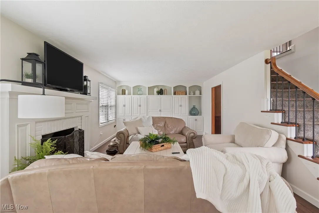 Living area with stairs, a fireplace, and wood finished floors
