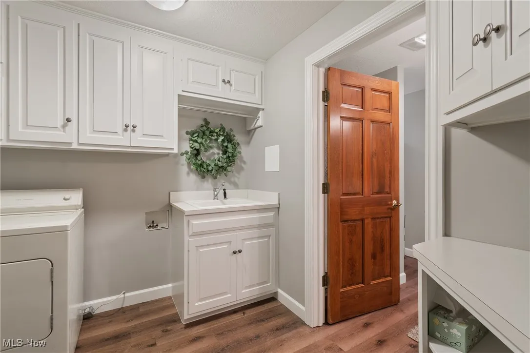 Washroom with washer / dryer, cabinet space, and wood finished floors