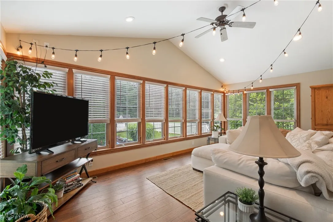 Living room with vaulted ceiling, ceiling fan, hardwood / wood-style floors, and recessed lighting